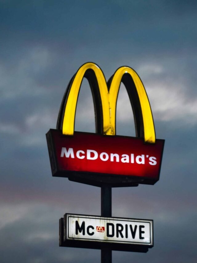 Photo by Capitalist Money on June 01, 2024. May be an image of A McDonald's sign stands tall against a cloudy evening sky. The iconic golden arches are illuminated, promising delicious food and convenient service. The image may contain text such as 'McDonald's', 'McDRIVE'.