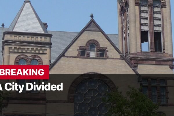 Photo by Capitalist Money on September 11, 2024. May be an image of A news headline that reads "Breaking: A City Divided" appears over the image of a large brick building, possibly a church. The image may contain text such as 'BREAKING', 'A City Divided'.