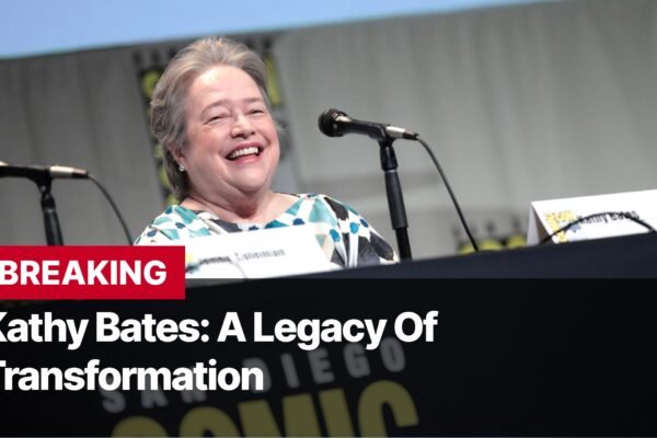 Photo by Capitalist Money on September 17, 2024. May be an image of Kathy Bates, renowned actress, smiles brightly while seated at a table with a microphone in front of her. She is at a panel discussion, possibly at a convention or film festival. The image may contain text such as 'BREAKING Kathy Bates: A Legacy Of Transformation'.