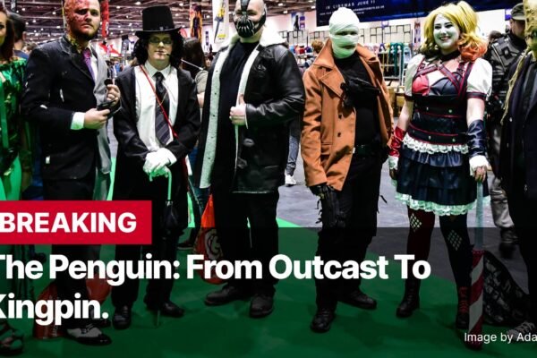 Photo by Capitalist Money on November 11, 2024. May be an image of A group of people dressed up in costumes, including Poison Ivy, Two-Face, The Penguin, Bane, and Harley Quinn. They are standing on a green floor, with a red banner in the foreground saying: "BREAKING The Penguin: From Outcast to Kingpin." The image may contain text such as 'BREAKING The Penguin: From Outcast To Kingpin. Image by AdamBMorgan'.