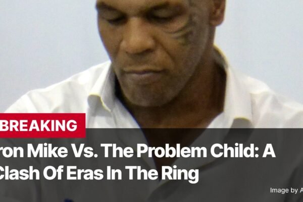 Photo by Capitalist Money on November 13, 2024. May be an image of Mike Tyson is pictured looking down, appearing to be thinking deeply. Text on the image states "Iron Mike Vs. The Problem Child: A Clash of Eras In The Ring." The image may contain text such as 'B', 'R', 'E', 'A', 'K', 'I', 'N', 'G', ' ', 'I', 'r', 'o', 'n', ' ', 'M', 'i', 'k', 'e', ' ', 'V', 's', '.', ' ', 'T', 'h', 'e', ' ', 'P', 'r', 'o', 'b', 'l', 'e', 'm', ' ', 'C', 'h', 'i', 'l', 'd', ':', ' ', 'A', ' ', 'C', 'l', 'a', 's', 'h', ' ', 'O', 'f', ' ', 'E', 'r', 'a', 's', ' ', 'I', 'n', ' ', 'T', 'h', 'e', ' ', 'R', 'i', 'n', 'g', ' ', 'I', 'm', 'a', 'g', 'e', ' ', 'b', 'y', ' ', 'A', 'n', 'i', 'm', 'a', 'l', 'p', 'a', 'r', 't', 'y'.