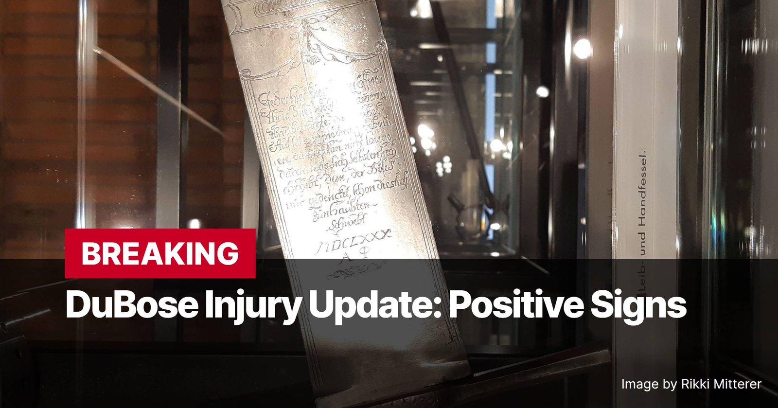 Photo by Capitalist Money on December 16, 2024. May be an image of Close-up view of an antique sword or dagger with intricate engravings on its blade, displayed in a glass case. The image is overlaid with text announcing a positive update on a DuBose injury. The image may contain text such as 'BREAKING', 'DuBose Injury Update: Positive Signs', 'Leib- und Handfessel.', 'Image by Rikki Mitterer', 'IDCLXXX'.